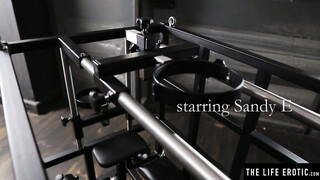 Kinky blonde Sandy E fingers her beaver in a BDSM cage